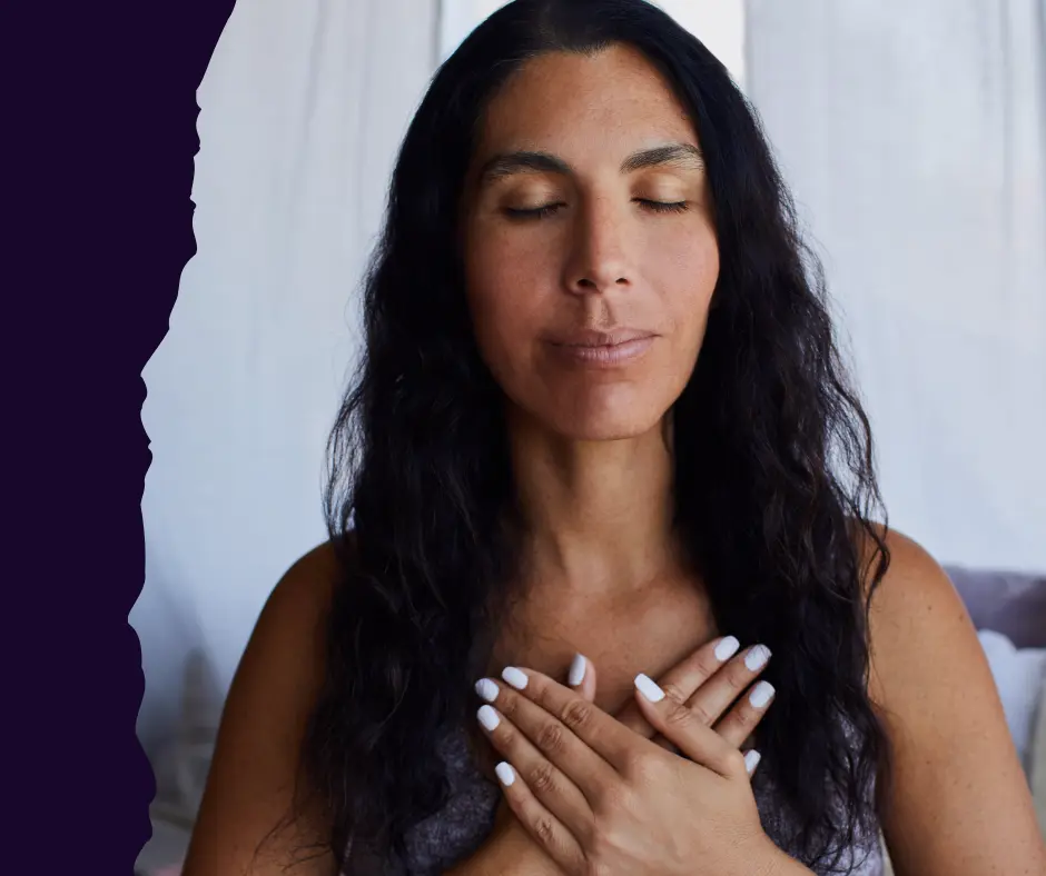 Woman practicing somatic emotional regulation with hand on heart to soothe nervous system.