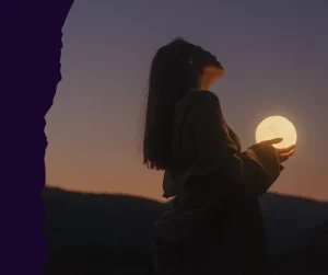 A woman in silhouette holding a glowing moon at sunset, representing the discovery of internal power and self-presence.